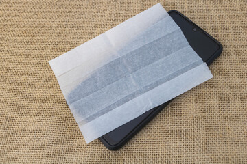 Smartphone with blank screen and wet wipe on sackcloth background