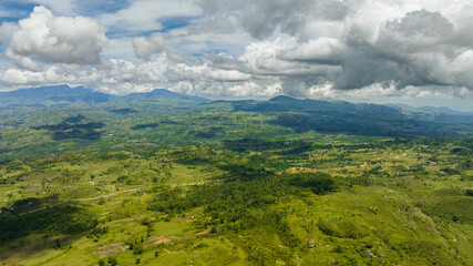 Fototapeta premium Aerial view of mountain landscape with green hills and farmland. Negros, Philippines