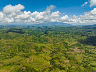 Obraz premium Farmland on a background of blue sky and clouds in a mountainous area. Negros, Philippines
