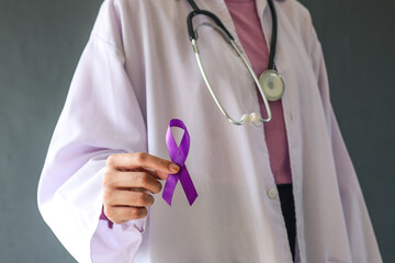 Doctor holding purple ribbon on grey background, closeup. Symbol of Domestic Violence Awareness and...