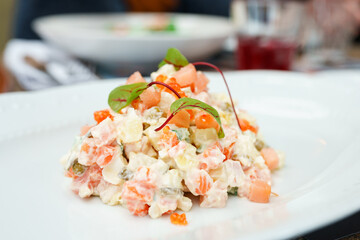 Olivier salad with salmon on a white plate