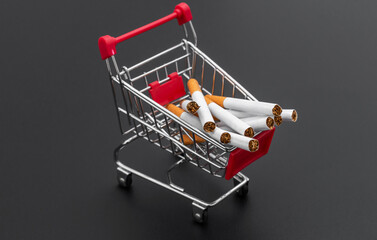Shopping cart with cigarettes on black background.
