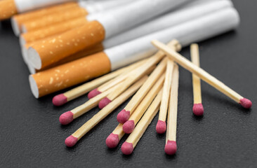 Matches with cigarettes on black background. Close up.