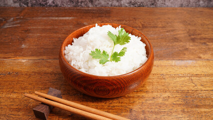 Hot cooked rice in brown wooden bowl