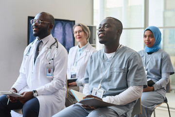 Obraz premium Group of doctors making notes during medical conference, they sitting on chairs and listening to speaker