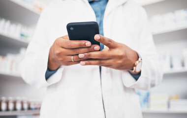 Hands, phone and healthcare with a pharmacist woman at work in a drugstore or dispensary for communication. Pharmacy, mobile and contact with a female medicine professional working in an apothecary