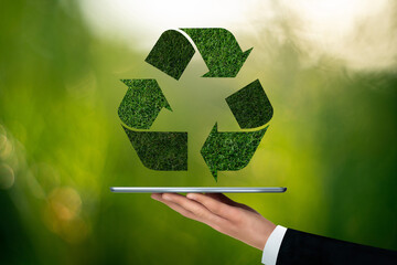 Businessman is holding a digital tablet with green recycling symbol. Concept