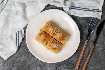 Baklava with milk and hazelnuts. Turkish cuisine delicacies. Baklava with milk on a dark background. Local name sutlu nuriye. Top view