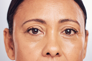 Closeup, portrait and eyes of a mature woman isolated on a studio background for skincare beauty....