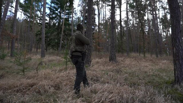 Soldier during a military operation, fully equipped camouflage on a reconnaissance military mission, rifles in firing position. They run in formation through the dense forest. Ukraine war