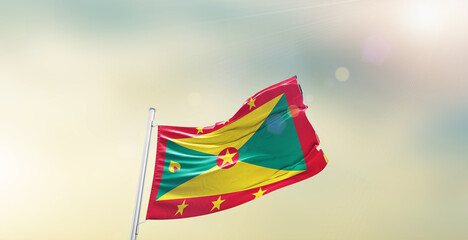 Waving Flag of Grenada on blur sky. The symbol of the state on wavy cotton fabric.