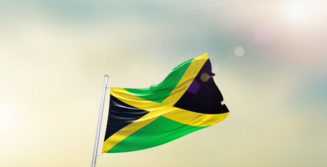 Waving Flag of Jamaica on blur sky. The symbol of the state on wavy cotton fabric.