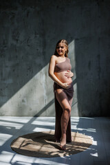 Smiling young pregnant woman in top and skirt posing in studio and stroking her belly. Pregnant pregnant woman. Happy pregnancy