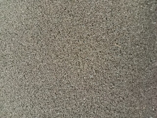 Black gray sponge surface with small holes.