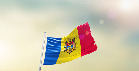 Waving Flag of Moldova on blur sky. The symbol of the state on wavy cotton fabric.