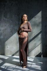 Young pregnant woman in beige top and skirt. Motherhood, pregnancy, copy space. Fashion for pregnancy. Happy period of pregnancy