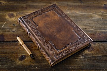 old book cover in brown leather with gilded the frame lay down to wooden table
