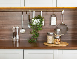 Contemporary kitchen background with kitchen utensils standing on wooden countertop, blank space for a text, front view