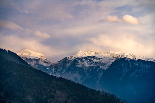 monsoon clouds moving over snow covered himalaya mountains with the blue orange sunset sunrise light over kullu manali valley