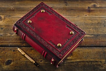 An Antique Old Aged Red Leather Book with a Beautifully Weathered Patina, Placed on a Rustic Wooden...