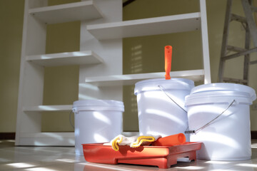 Paint bucket, paint tray, paint roller with metal stepladder in interior room preparing for painting wall, fixing and renovation room by self at home, house or apartment. Home renovation self concept.
