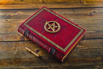 Red leather book with Ouroboros, pentagram and ancient Egyptian Symbols, lay down to wooden table