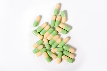 Close up shots of medicine tablets and capsules on white background. White and colored tablets placed in a group.