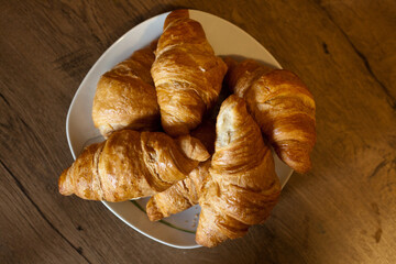 Croissants arranged in a plate placed on a wooden table