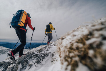Hiking and trekking in winter mountains. Adventure on a hiking trail, using backpack and trekking poles. Active lifestyle, outdoor sports. - obrazy, fototapety, plakaty