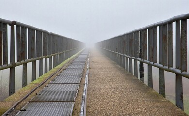 Obraz premium Landscape of a bridge with old metal rusty fences under a cloudy sky and sunlight