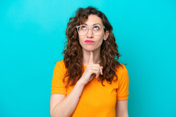 Young caucasian woman isolated on blue background With glasses and looking up