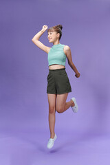 Full length portrait of a joyful young woman jumping and celebrating