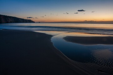 Obraz premium Maslins beach at dawn with fiery and purple clear sky backkground