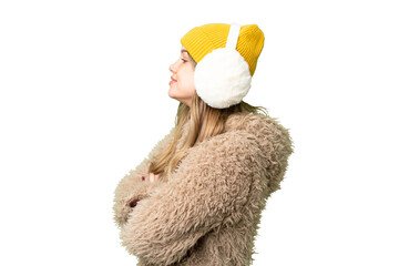 Young girl wearing winter muffs over isolated chroma key background in lateral position