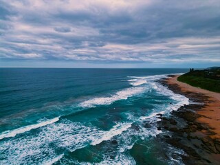 Fototapeta na wymiar Scenic view of a blue sea with a rocky coastline in cloudy sky background
