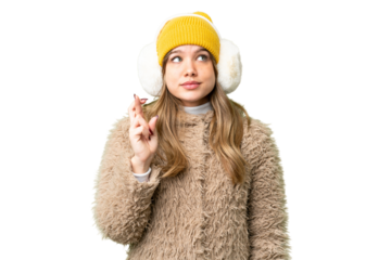 Young girl wearing winter muffs over isolated chroma key background with fingers crossing and wishing the best
