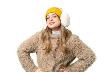 Young girl wearing winter muffs over isolated chroma key background posing with arms at hip and...