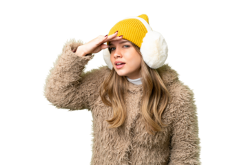 Young girl wearing winter muffs over isolated chroma key background looking far away with hand to look something
