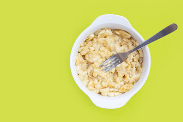 Mashed bananas in bowl on green background.