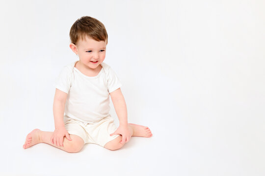 A happy baby is sitting on a studio white background. Full-length portrait of a smiling child. Kid aged about two years (one year nine months)