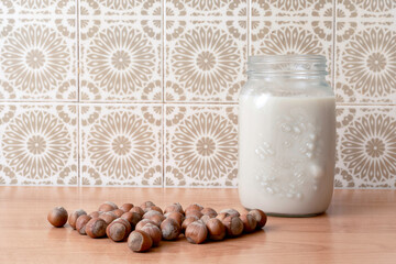 Non-diet vegan hazelnut milk with whole hazelnuts on rustic wooden background. Lactose-free hazelnut drink is an alternative vegetable milk. Healthy dairy product, close-up