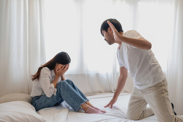 Internal violence. family conflict Men attack and beat women at home. Frightened woman covering her face sitting on the bed. She was scared.