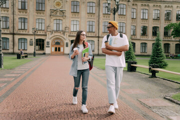 two international students, a man and a woman, walk through the selections and communicate amicably against the backdrop of the campus