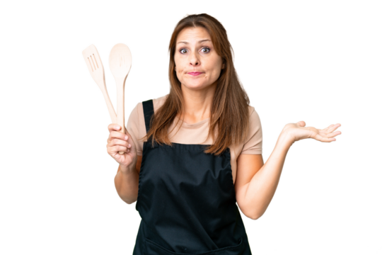 Middle age caucasian woman holding a rolling pin over isolated background having doubts while raising hands - Powered by Adobe