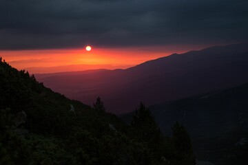 Scenic shot of the rising sun and the colorful sky illuminating the mountainside