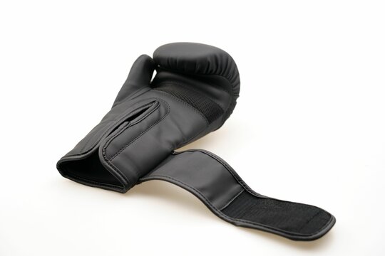 Single black boxing glove with an open strap isolated on a white background