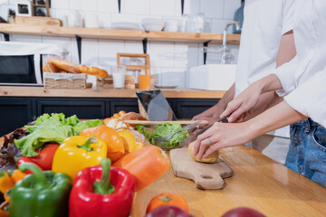 Young Asian couple cooking with fruits and vegetables and using laptop in the kitchen To cook food together within the family happily, family concept.