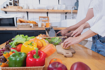 Young Asian couple cooking with fruits and vegetables and using laptop in the kitchen To cook food together within the family happily, family concept.