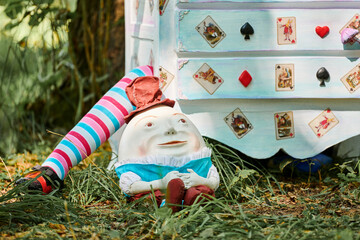 Dresser with doll Alice inside near Humpty Dumpty and mushrooms art object on outdoor art...