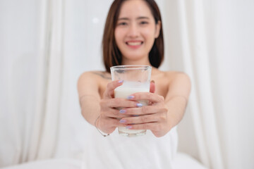 Portrait of young cheerful Asian woman drinking healthy milk on the morning of the holiday Good rest and healthy lifestyle concept.